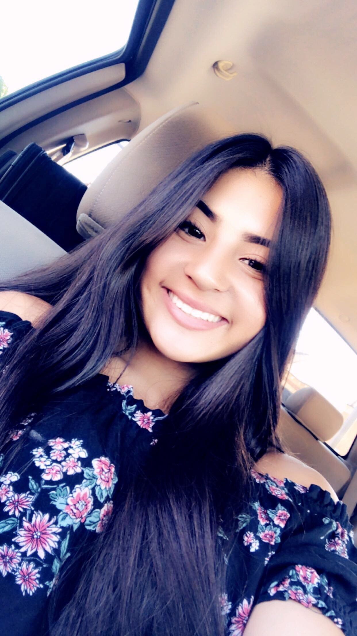 A woman is smiling while sitting in the back seat of a car.