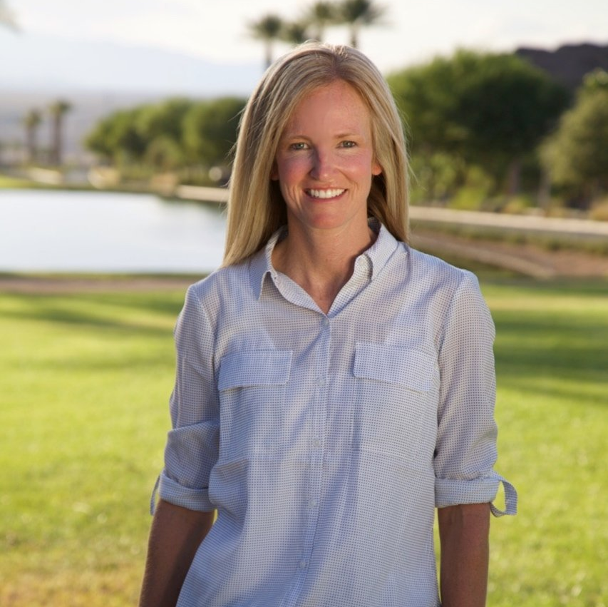 A woman in a white shirt is standing in a grassy field