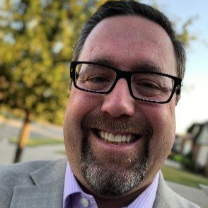 A man with glasses and a beard is smiling for the camera.