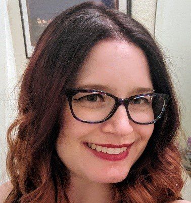 A little girl with a white bow in her hair is smiling for the camera.