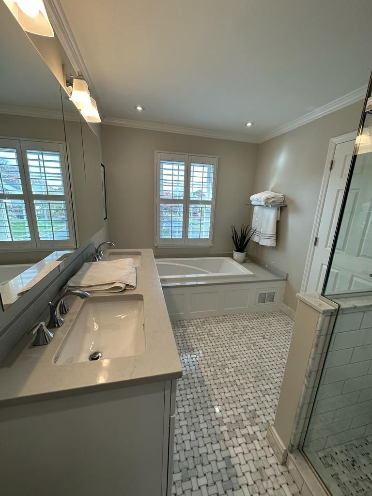 A bathroom with two sinks , a tub and a mirror.
