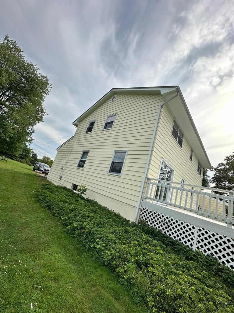 A large white house is sitting on top of a grassy hill.