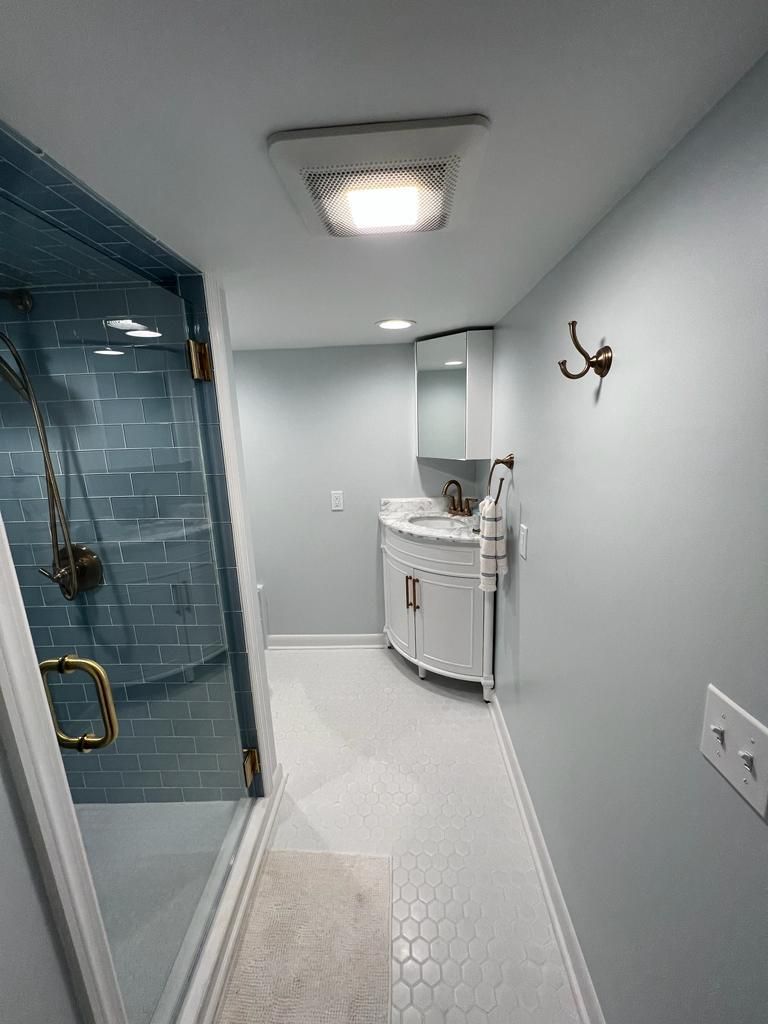 A bathroom with a walk in shower , sink and mirror.
