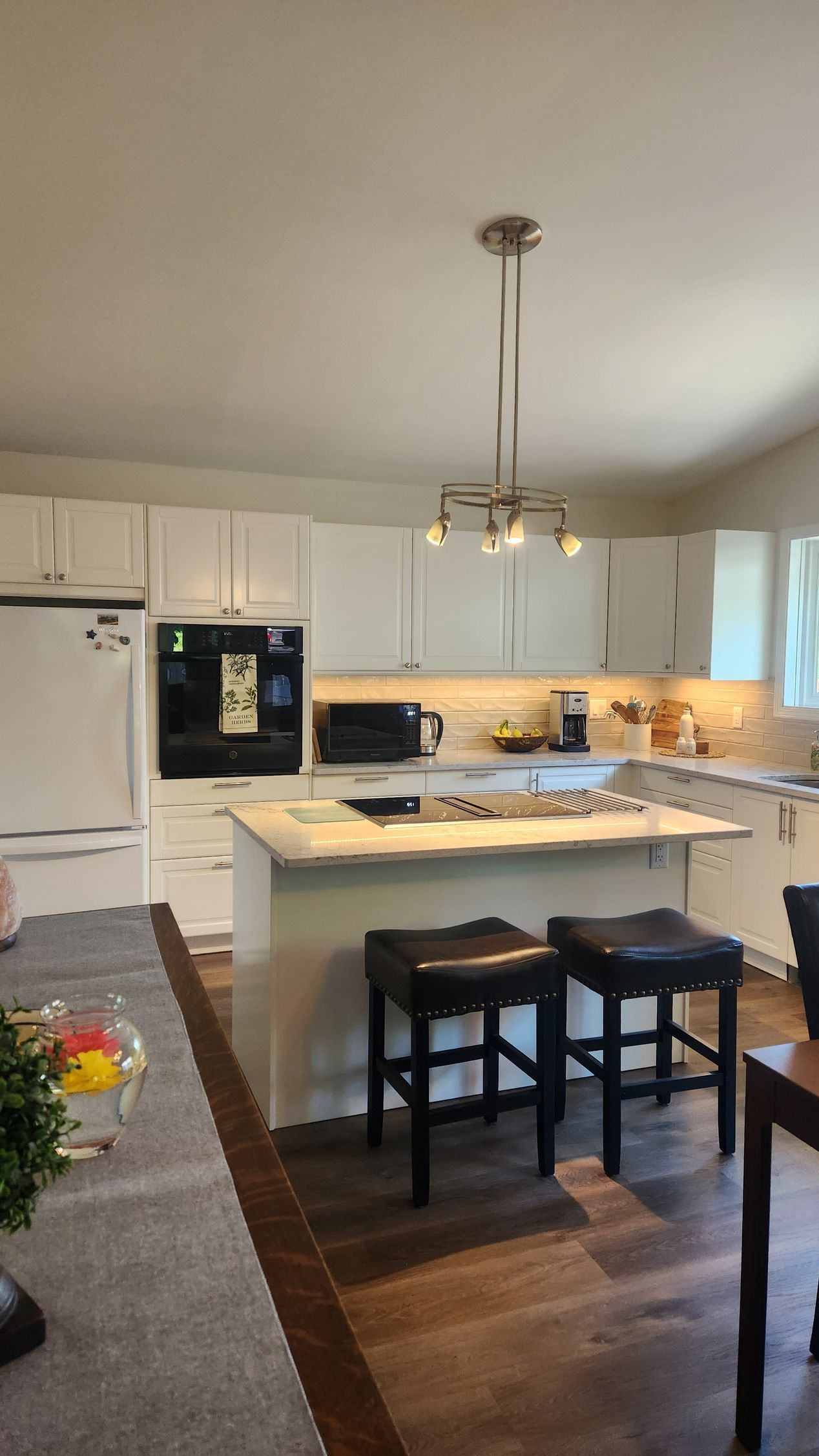 A kitchen with white cabinets and black stools