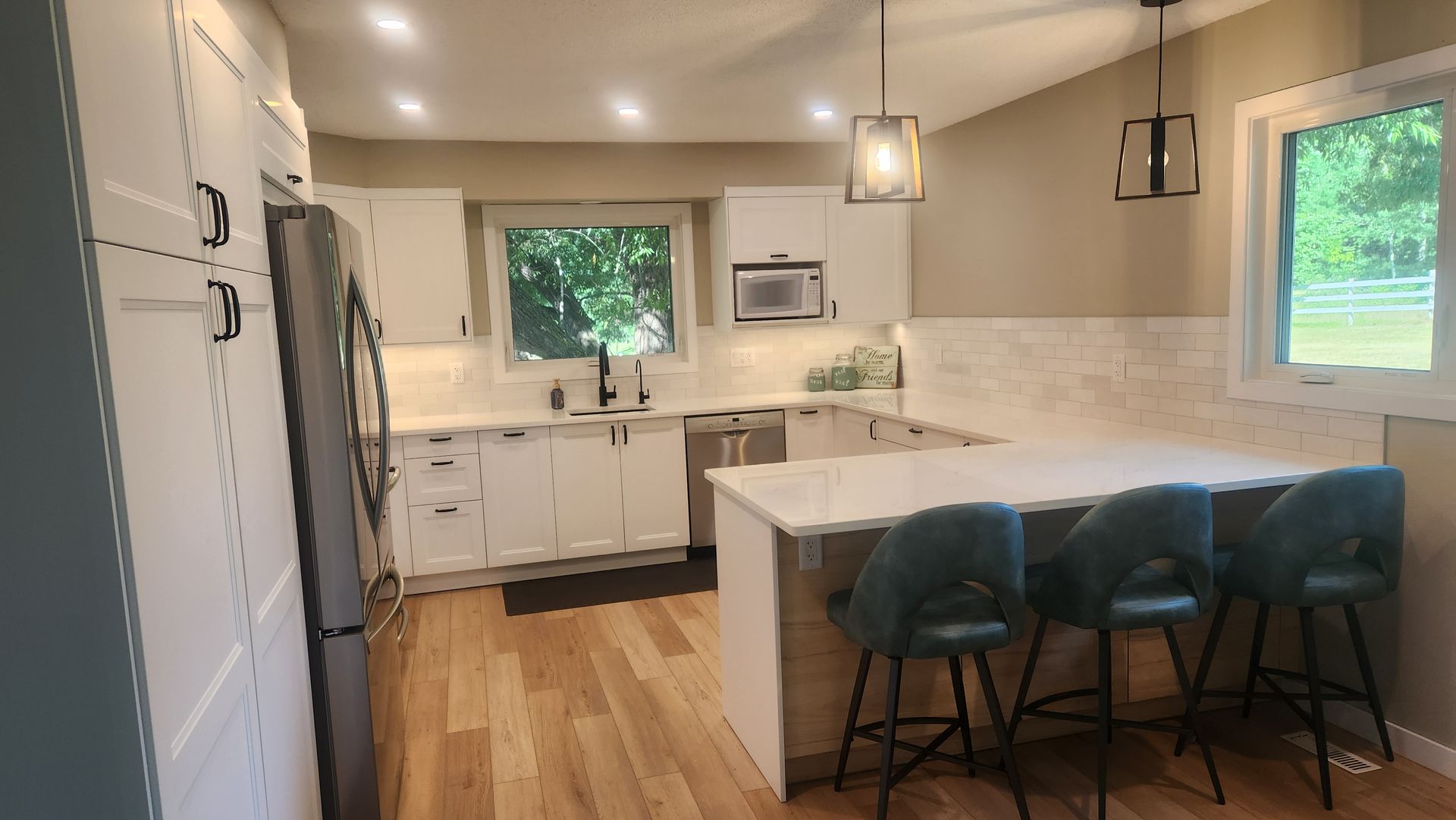 A kitchen with white cabinets , stainless steel appliances , hardwood floors and a large island.