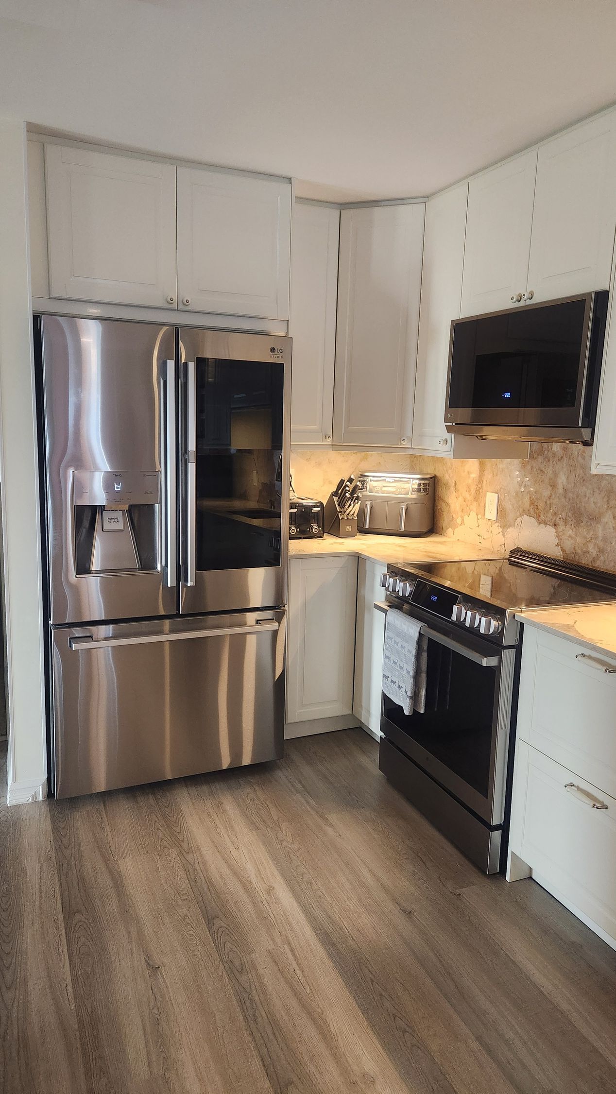 A kitchen with stainless steel appliances and white cabinets.