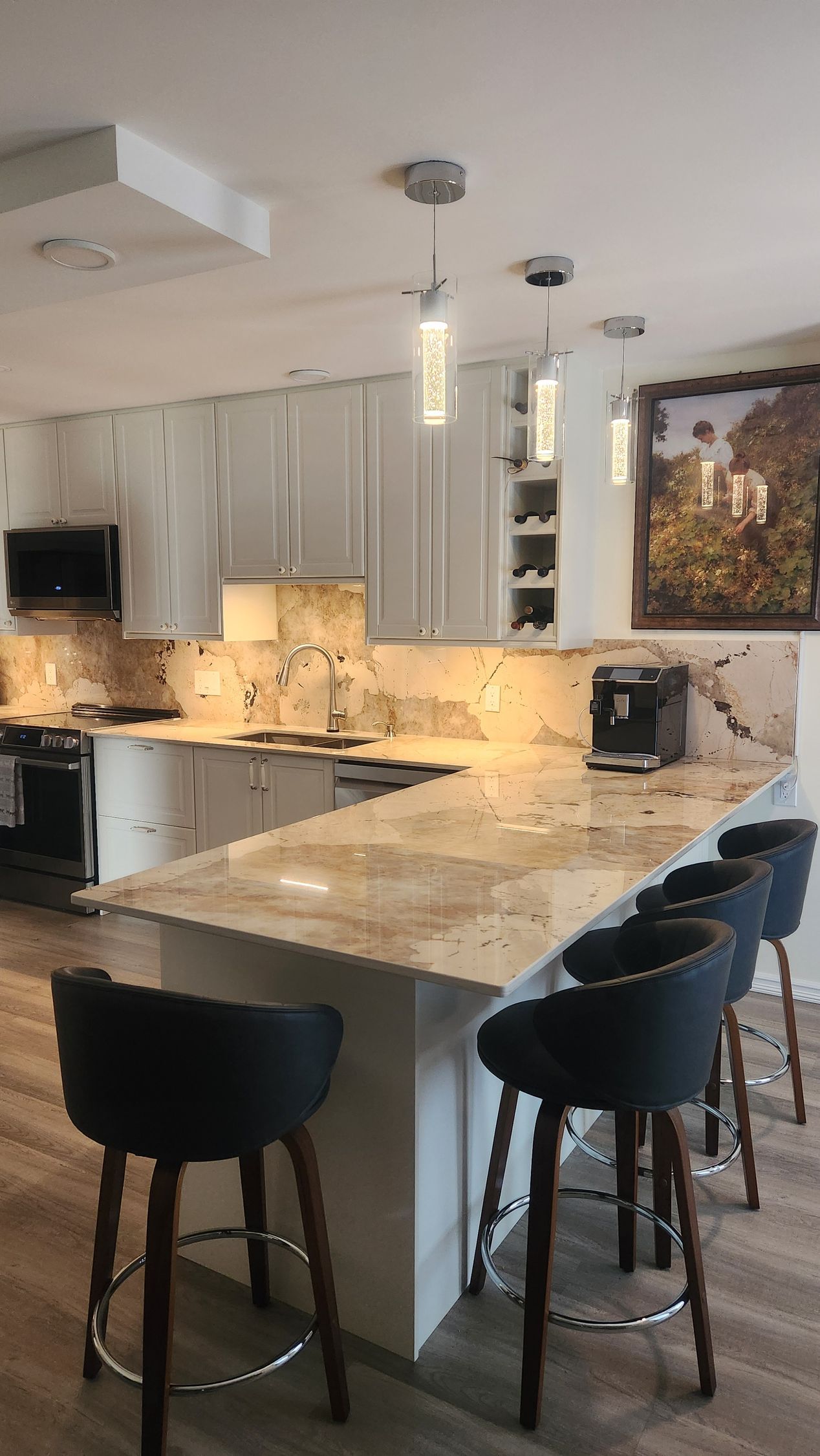 A kitchen with a large island and stools and a picture on the wall.