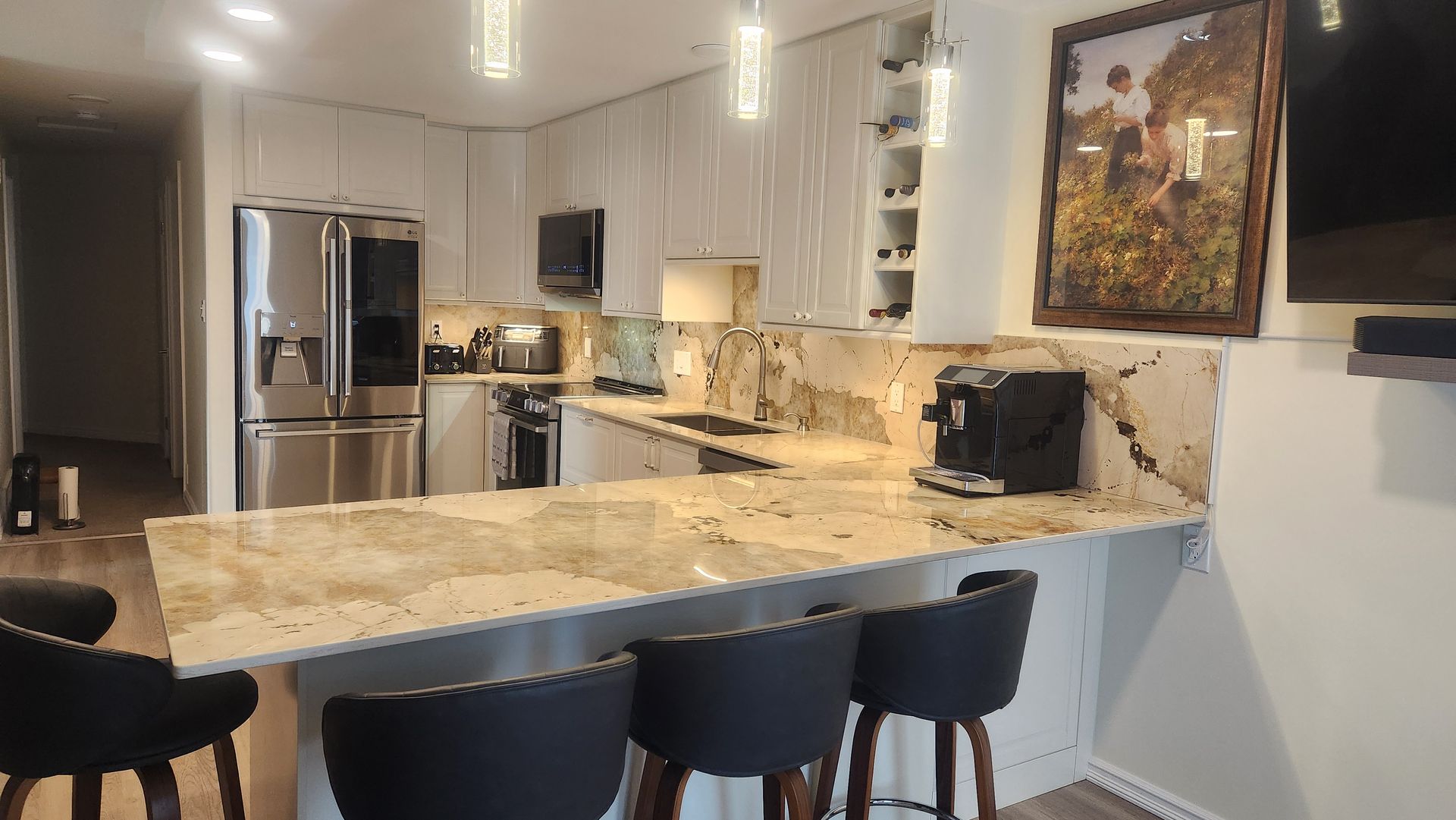 A kitchen with granite counter tops , stainless steel appliances , a refrigerator , and a bar.