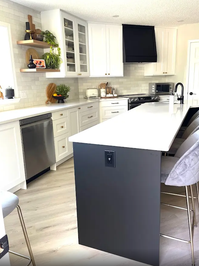 A kitchen with white cabinets , stainless steel appliances , and a large island.