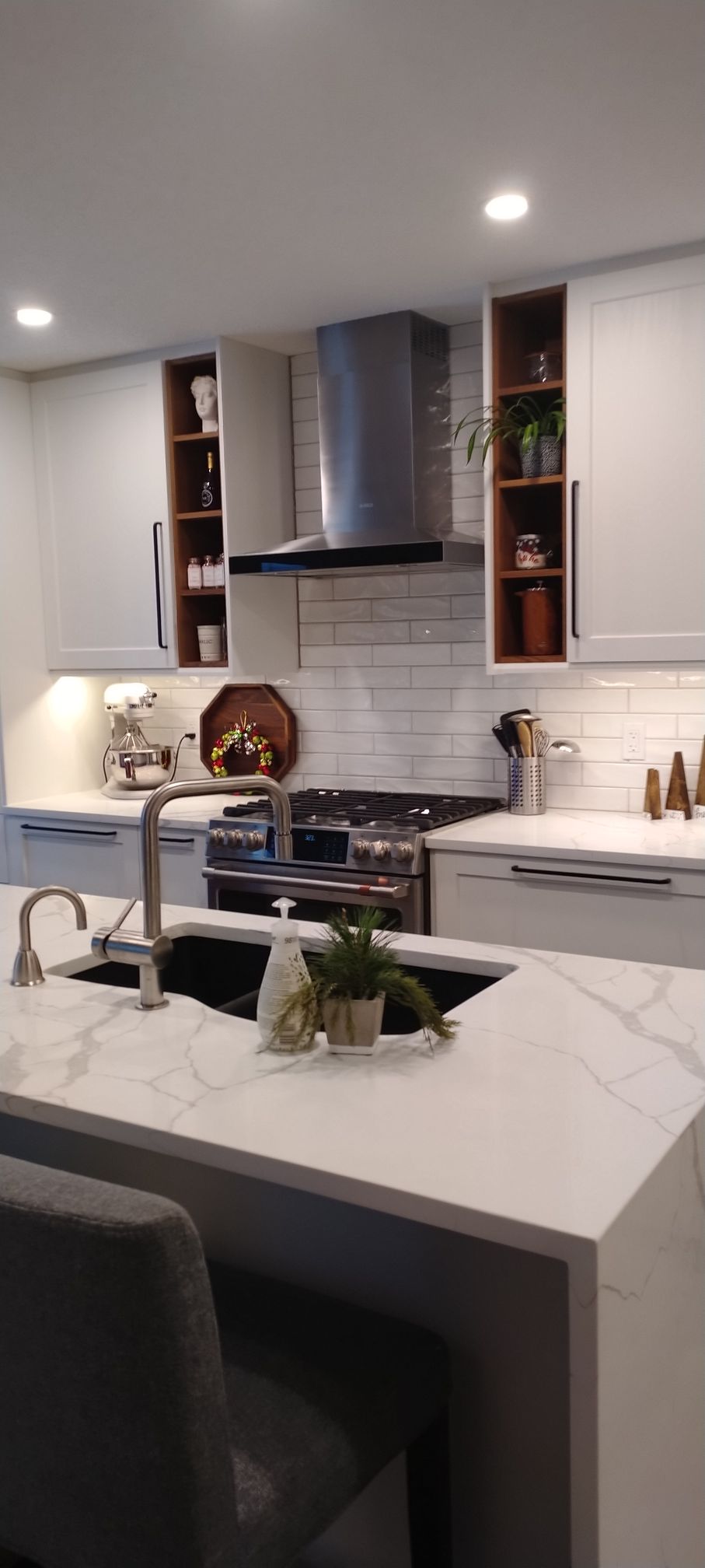 A kitchen with white cabinets , a sink , a stove , and a hood.