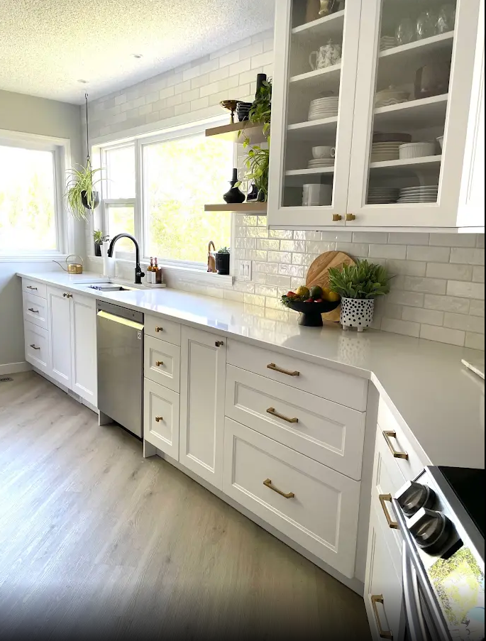 A kitchen with white cabinets , stainless steel appliances , and a large window.