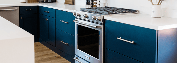 A kitchen with blue cabinets and a stove and oven.