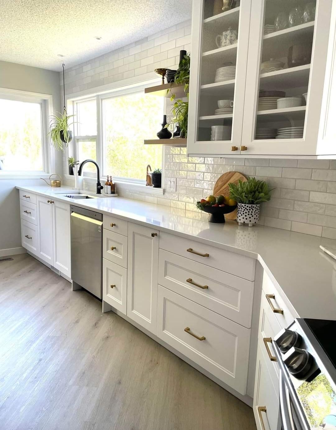 A kitchen with white cabinets , stainless steel appliances , and a large window.