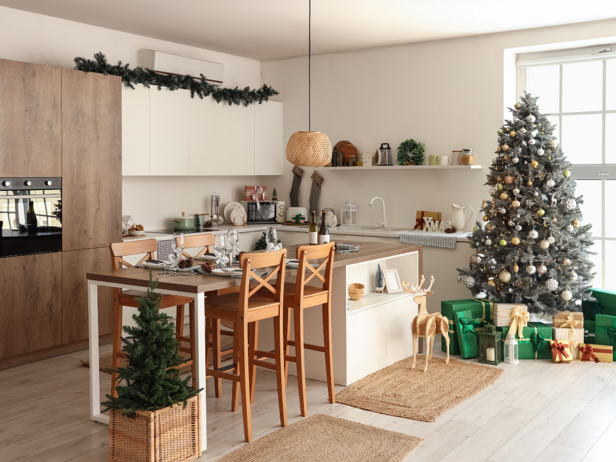Festive kitchen with Christmas tree, gifts, and a decorated island table.
