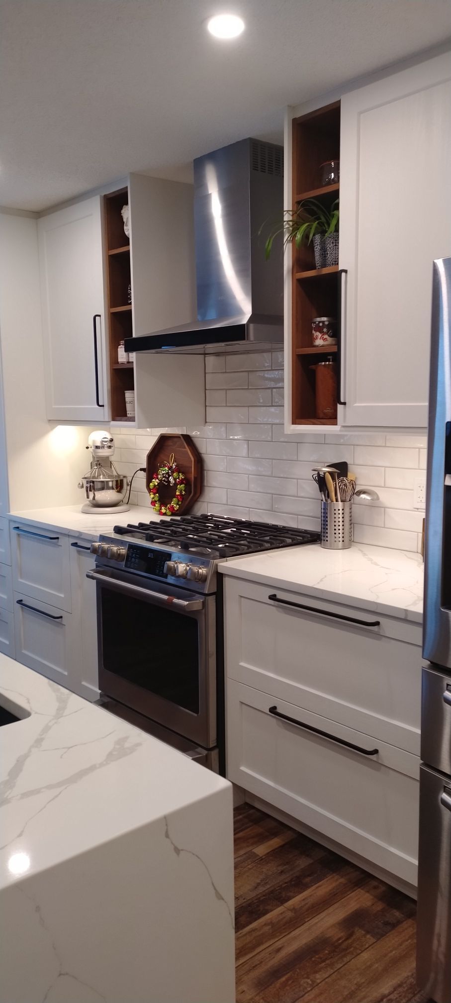 A kitchen with white cabinets , stainless steel appliances , a stove and a refrigerator.