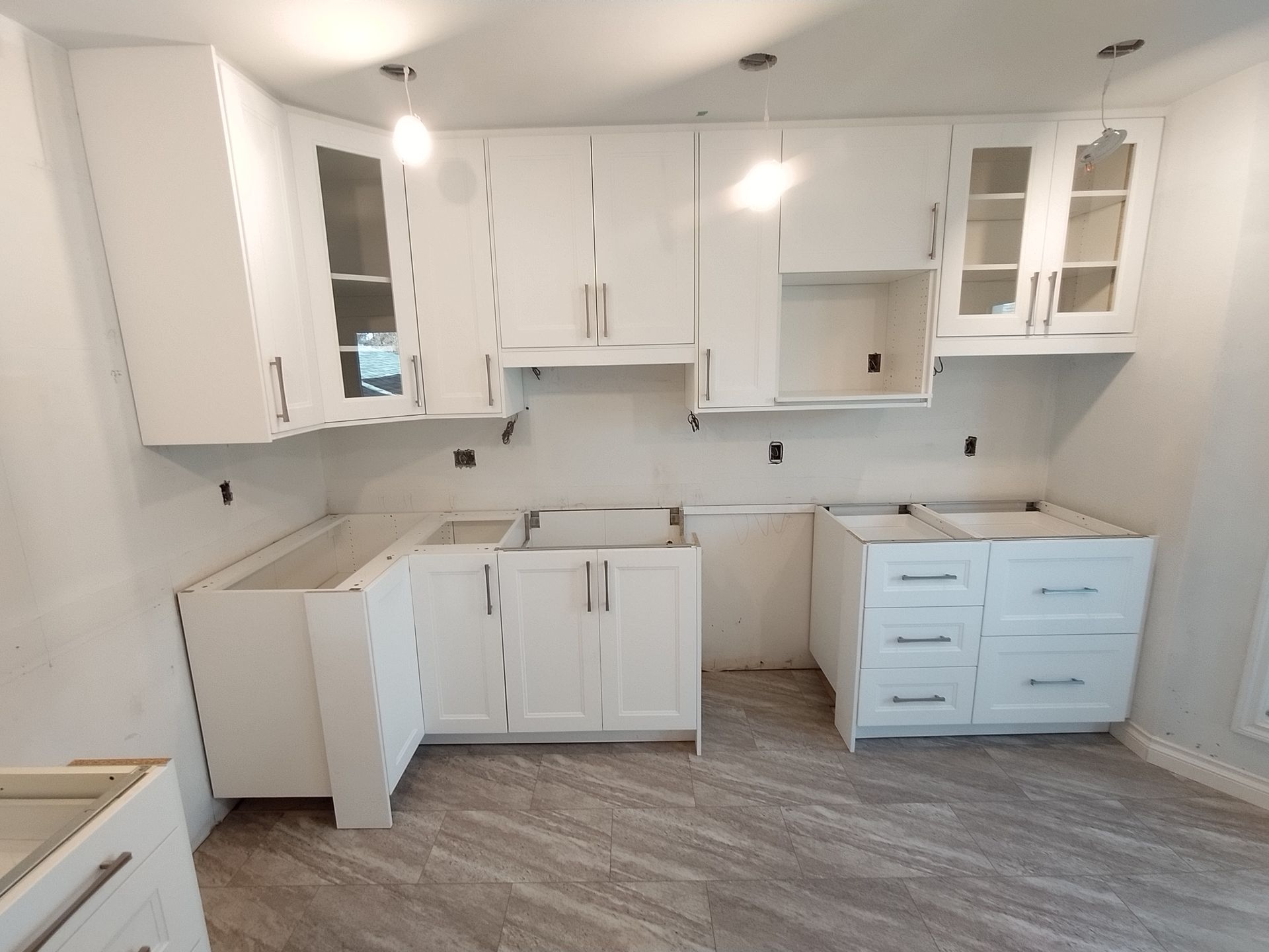 A kitchen with white cabinets and drawers under construction