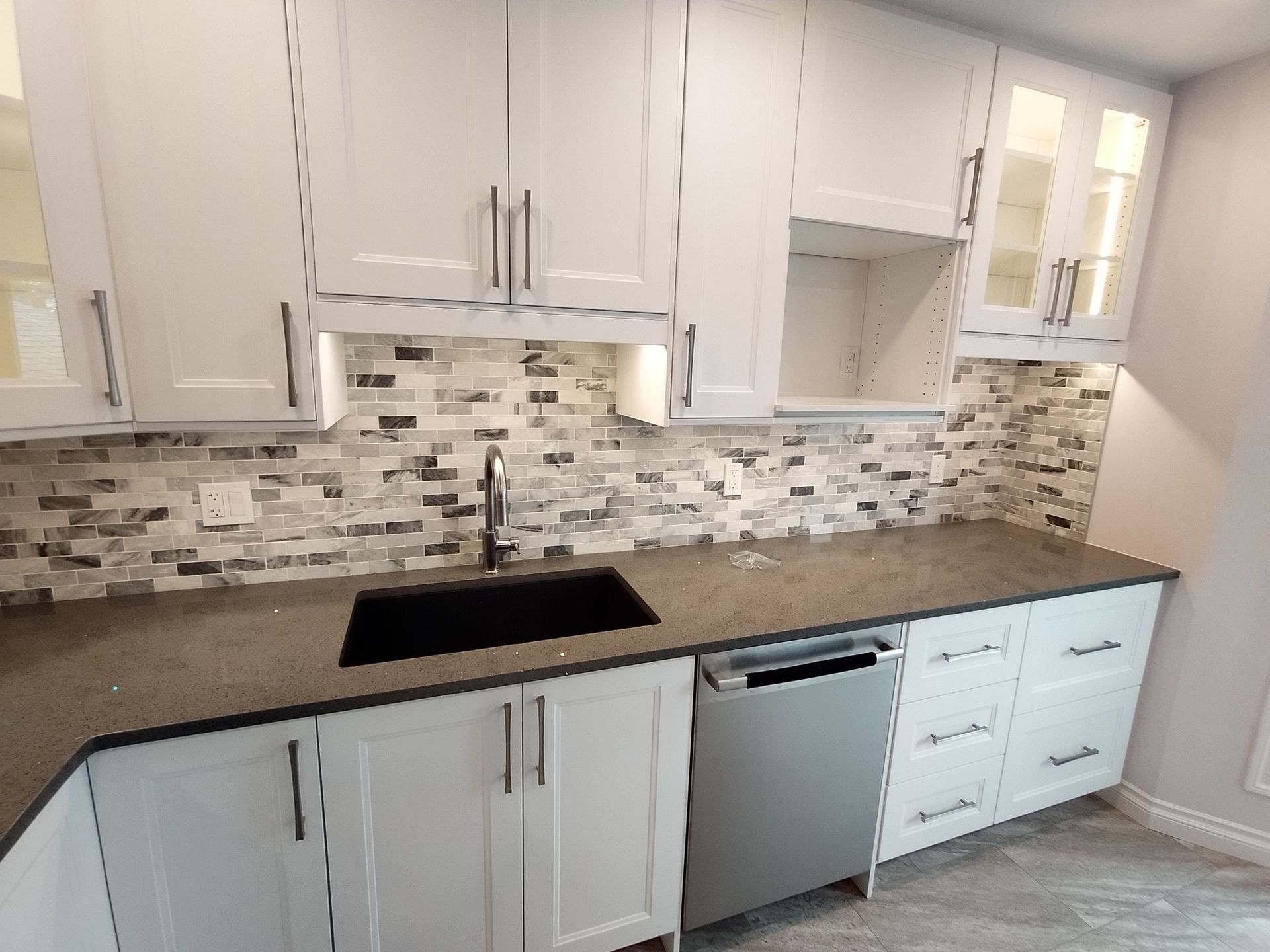 A kitchen with white cabinets , a sink , and a dishwasher.