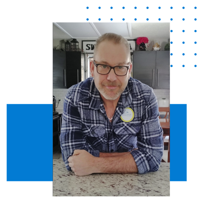 A man wearing glasses and a plaid shirt is sitting at a counter.