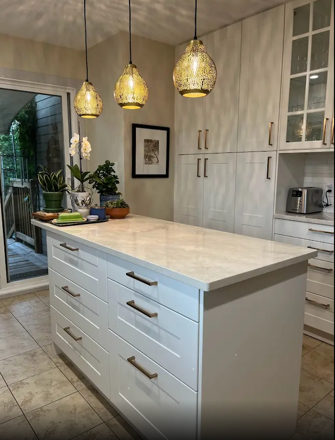 A kitchen with white cabinets and a large island in the middle.