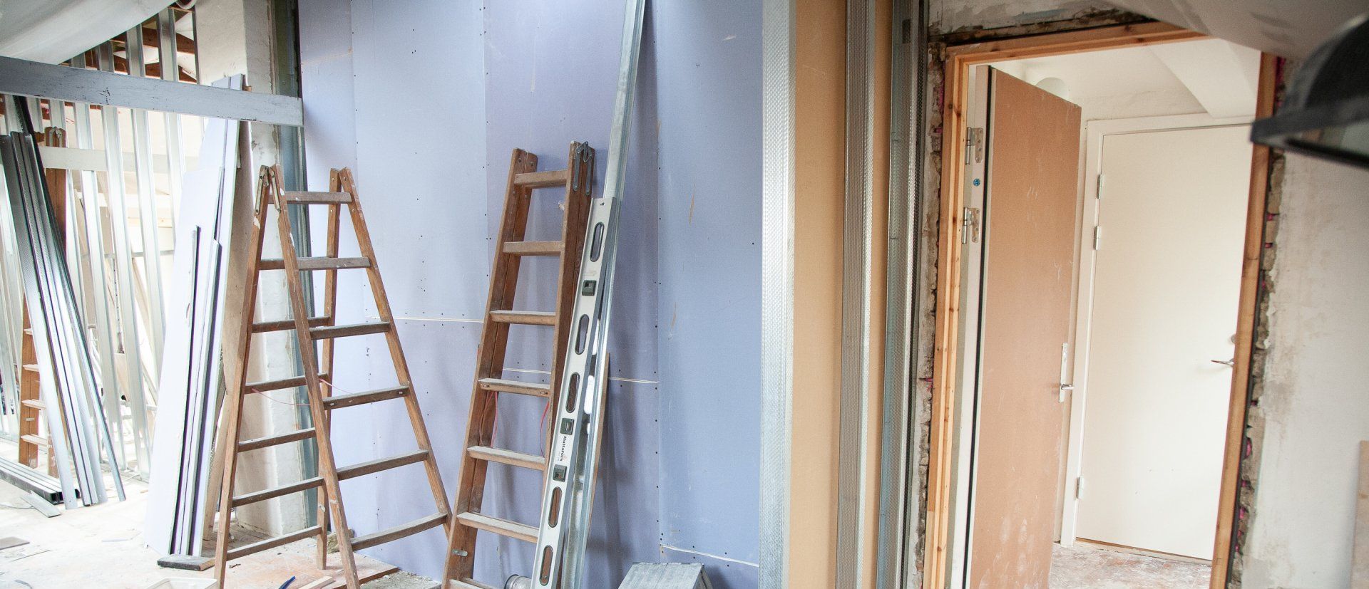 A room under construction with ladders and a door.