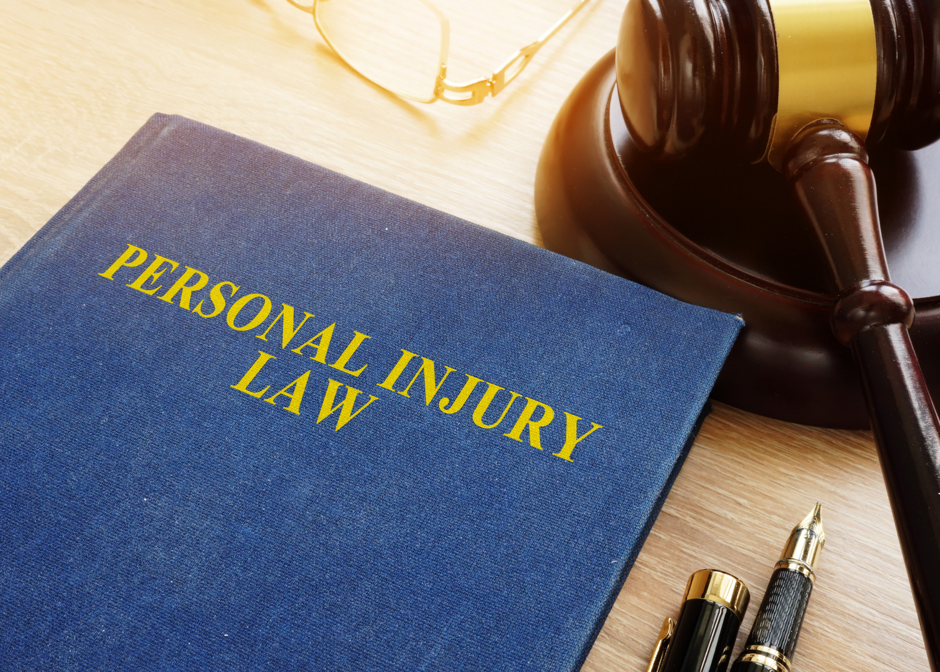 a personal injury law book is sitting on a wooden table next to a judge 's gavel .