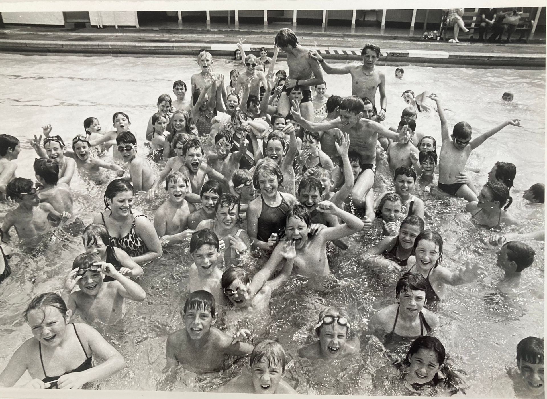 A large group of children are swimming in a pool