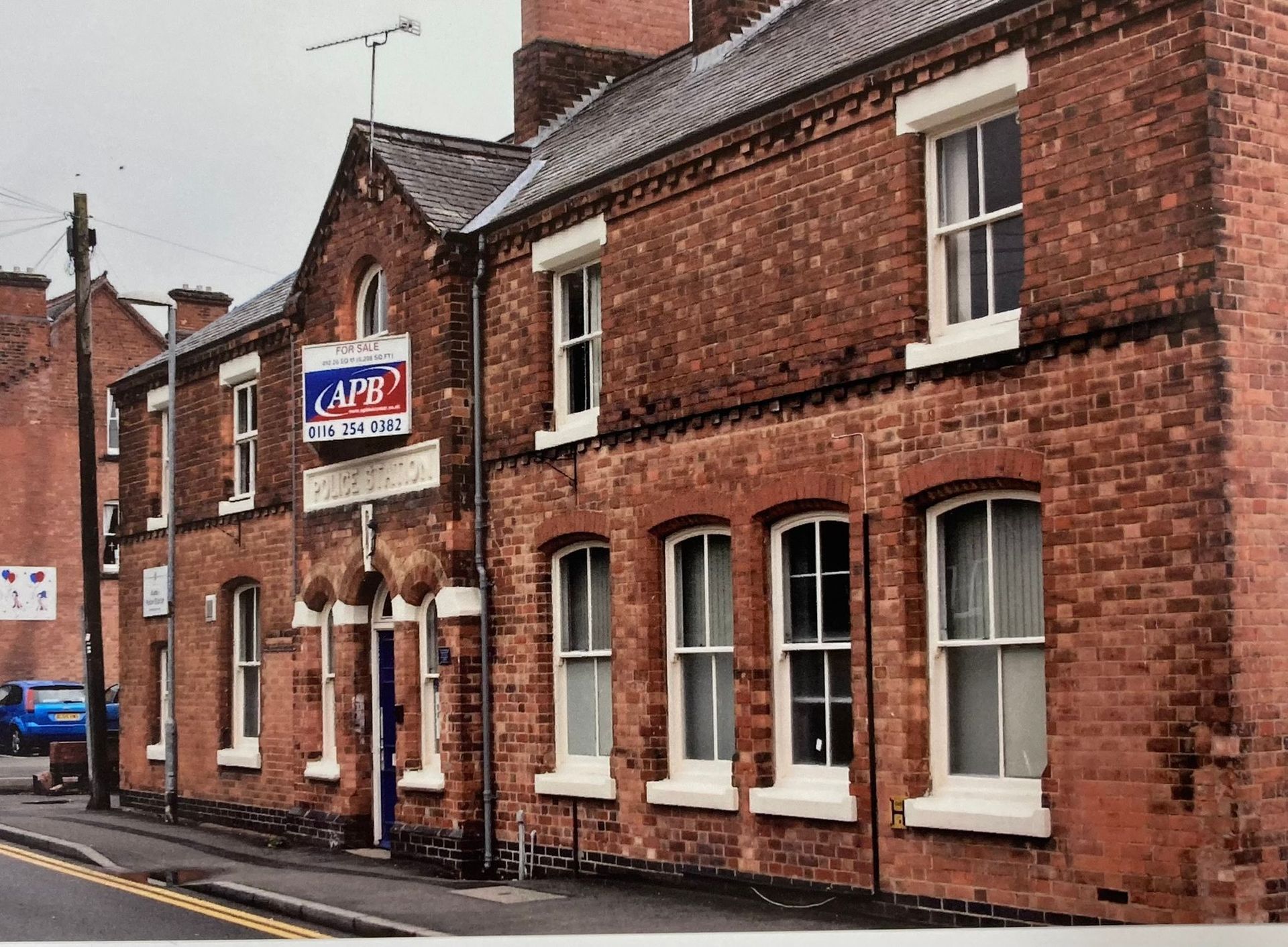 A brick building with a for sale sign in front of it