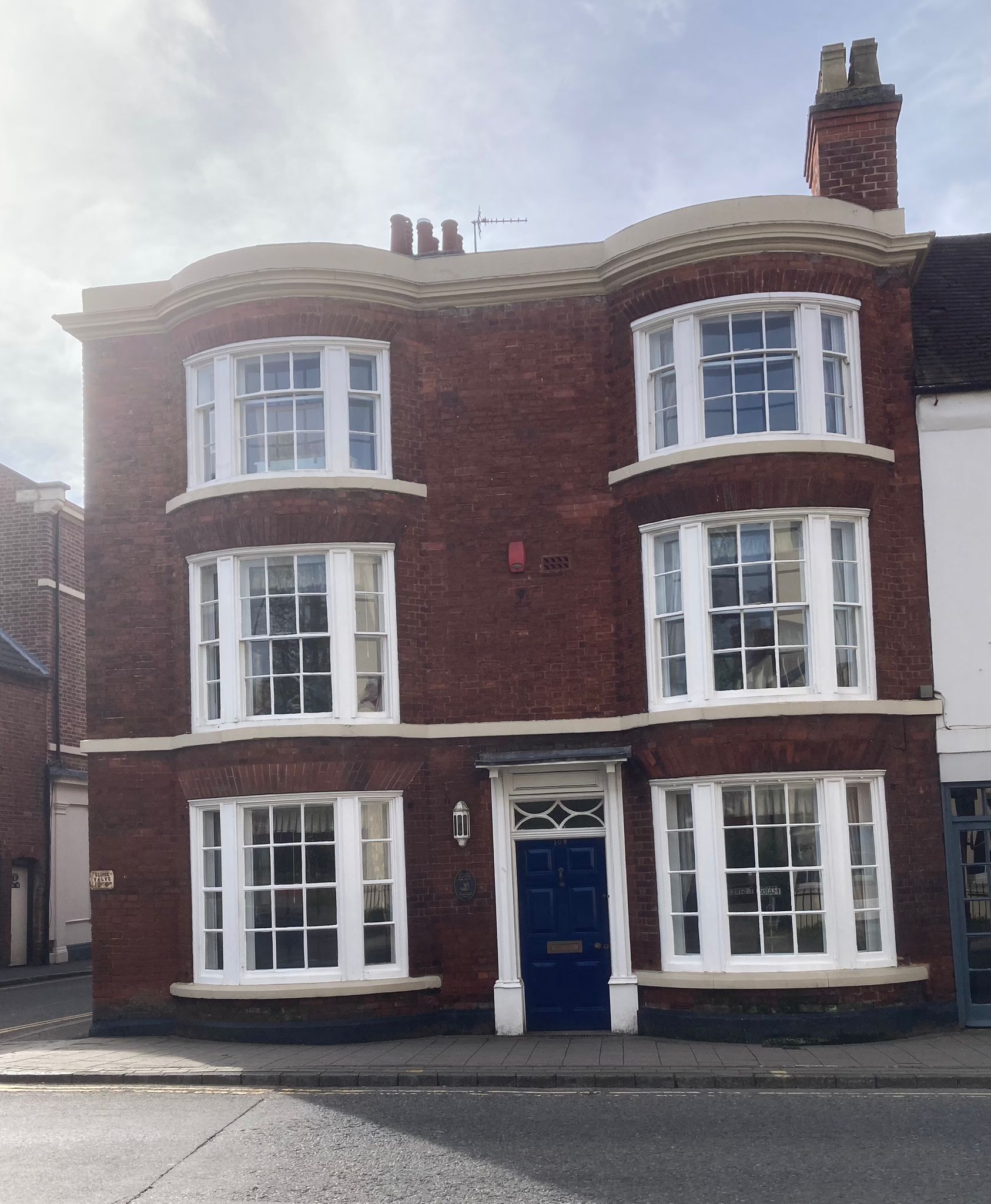 A red brick building with white windows and a blue door