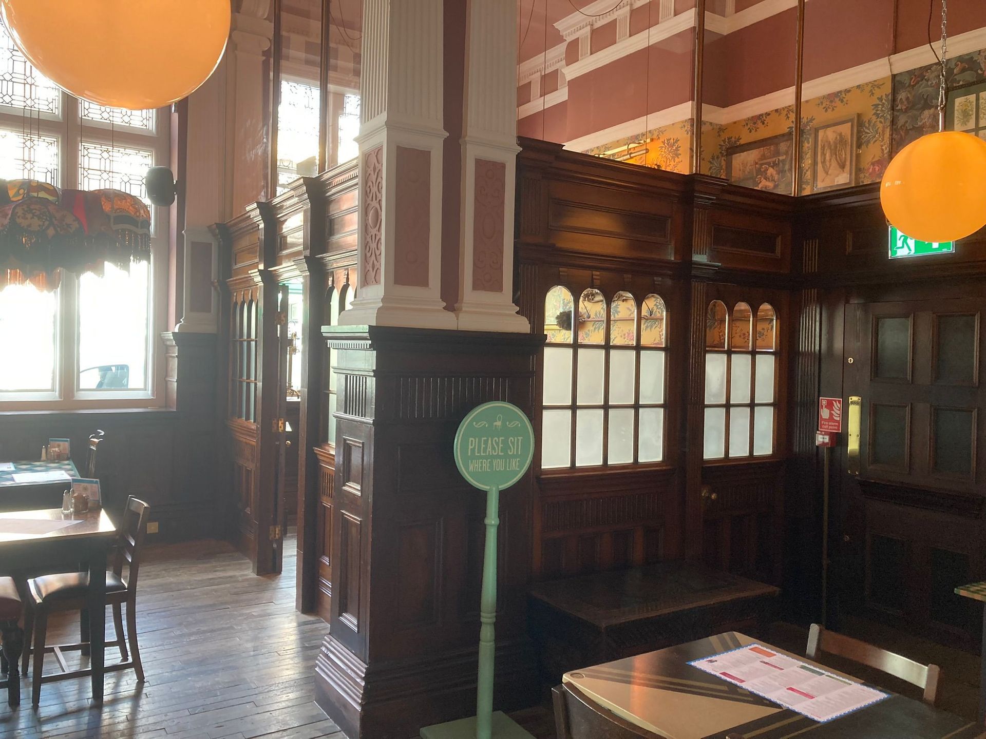 A restaurant with tables and chairs and a green scale hanging from the ceiling.
