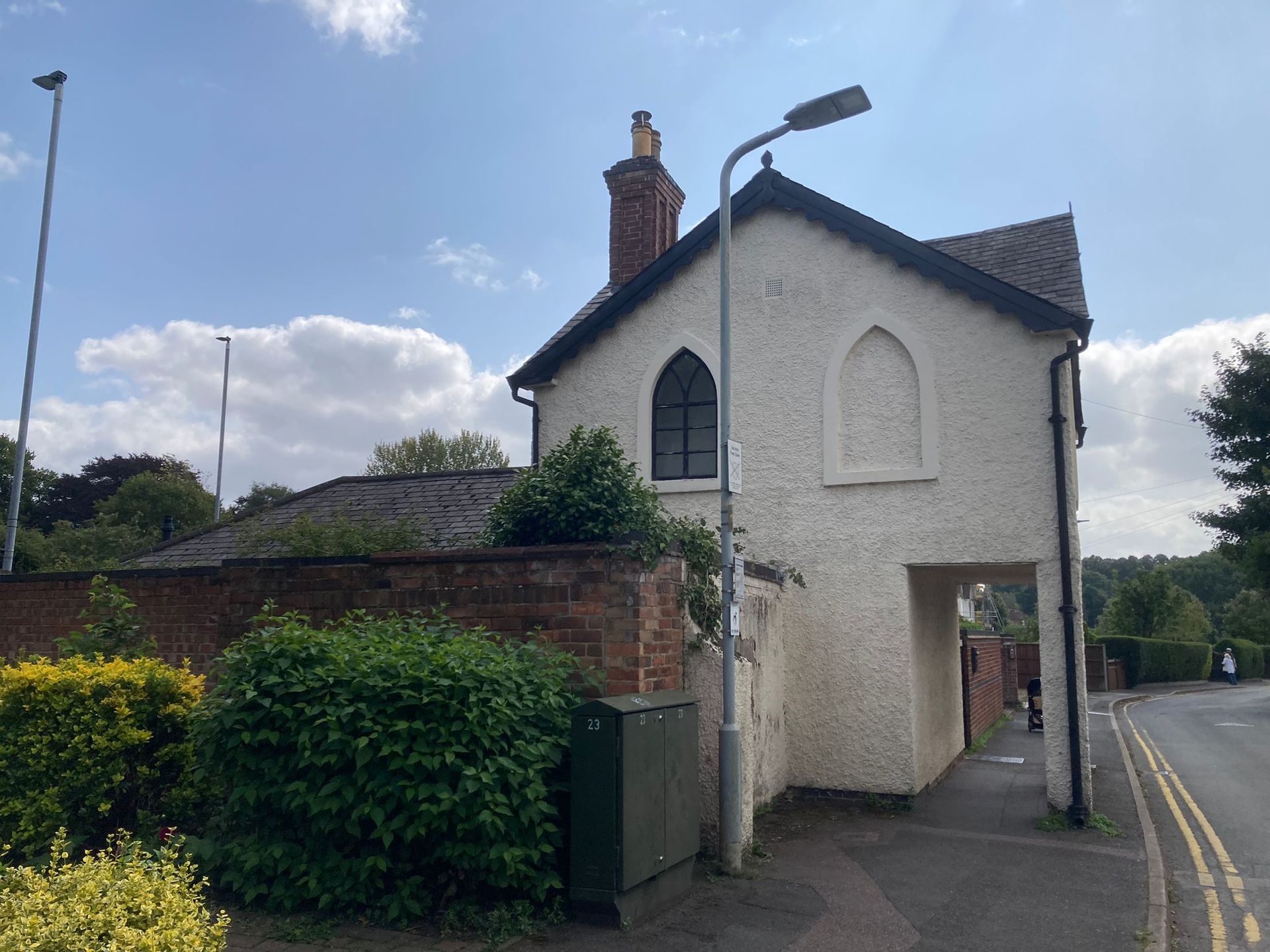 A small white building with a black roof is sitting on the side of a road of the Priest House 2024.