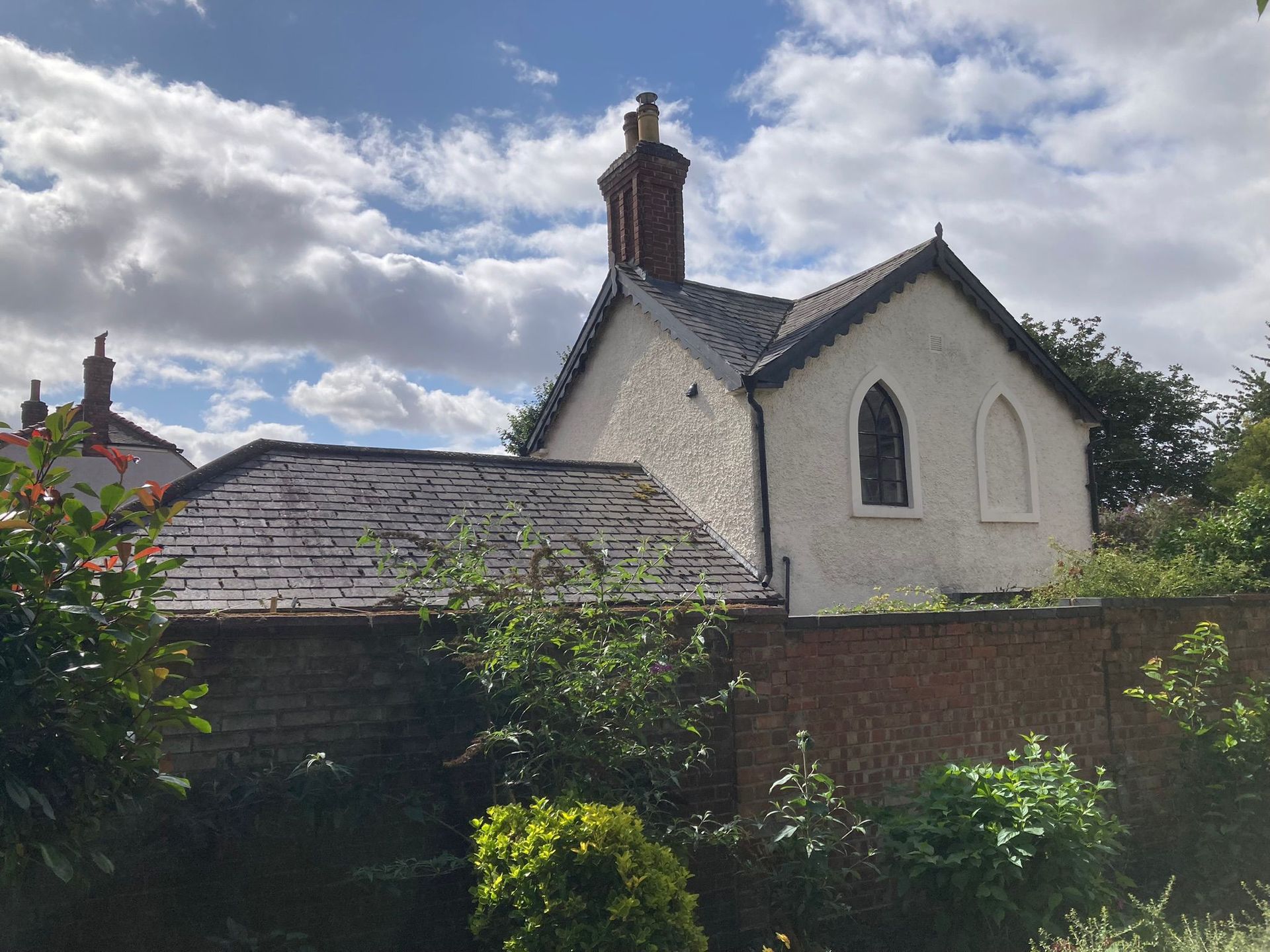 A small white house with a slate roof and a window of the Priest House 2024.