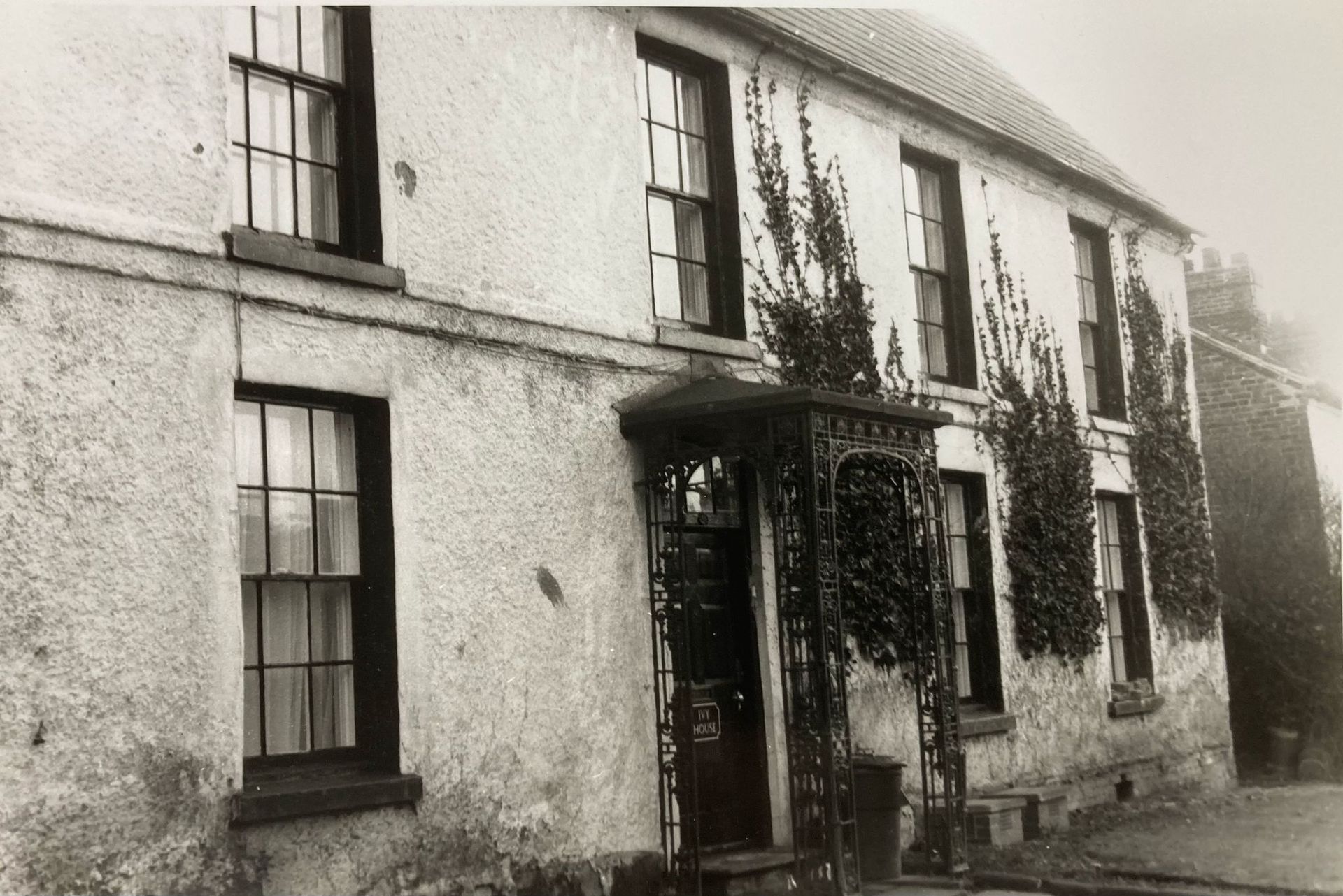 A black and white photo of a house with a porch