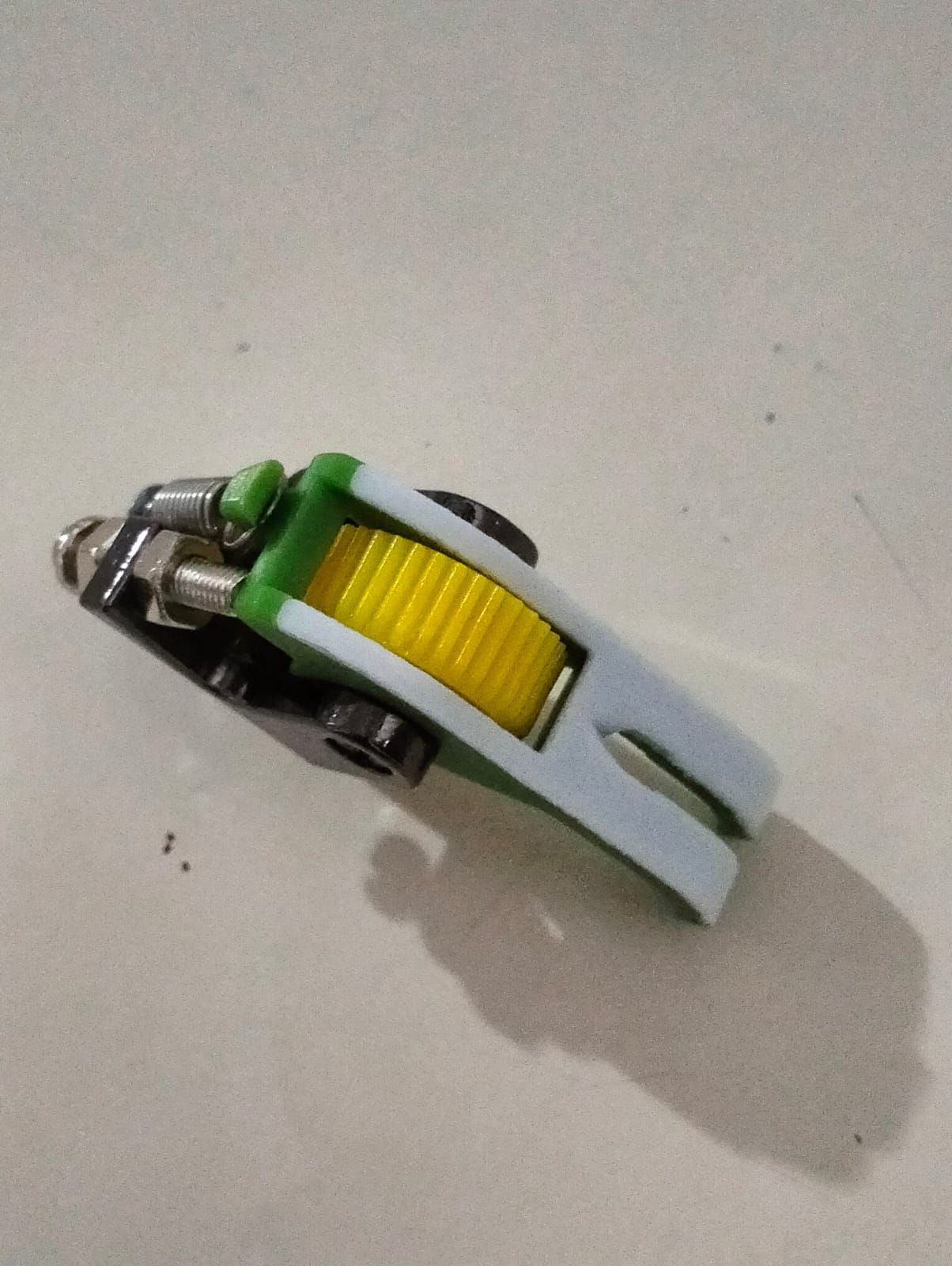 Prensatelas para máquina de coser de color verde y amarillo con base negra.