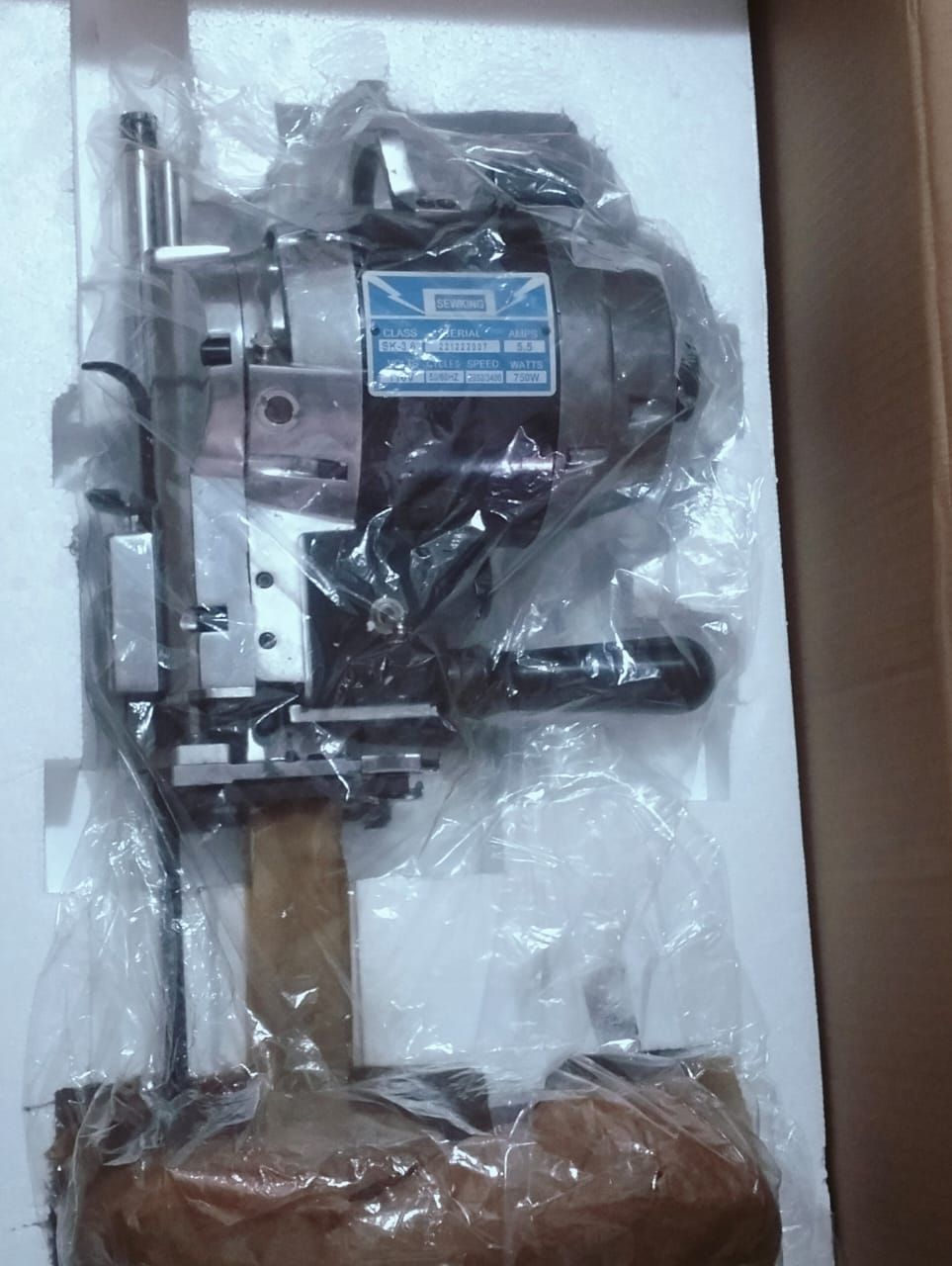 Una máquina industrial, todavía en embalaje, con motor y varios componentes metálicos, lista para usar.