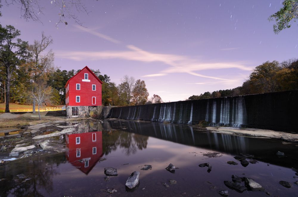 a red barn is reflected in a body of water