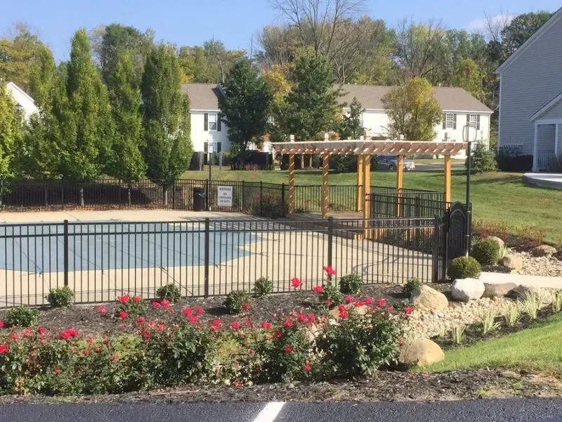 A fence surrounds a swimming pool in a residential area