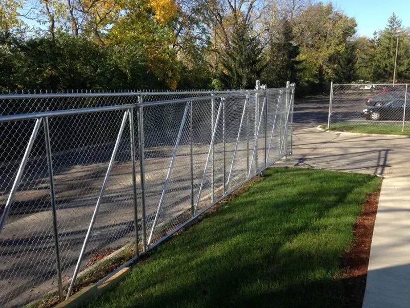 A chain link fence surrounds a lush green field