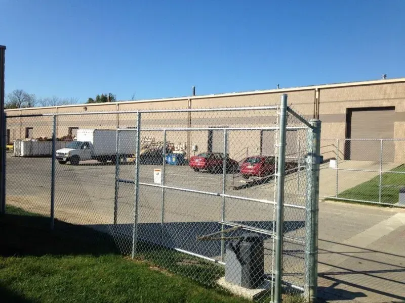 A white fence surrounds a lush green yard in front of a house