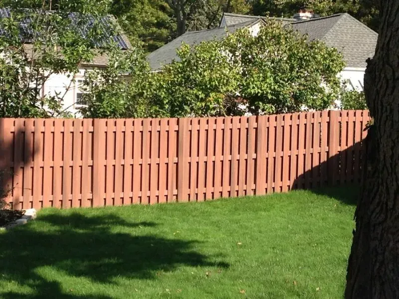 A wooden fence surrounds a lush green yard