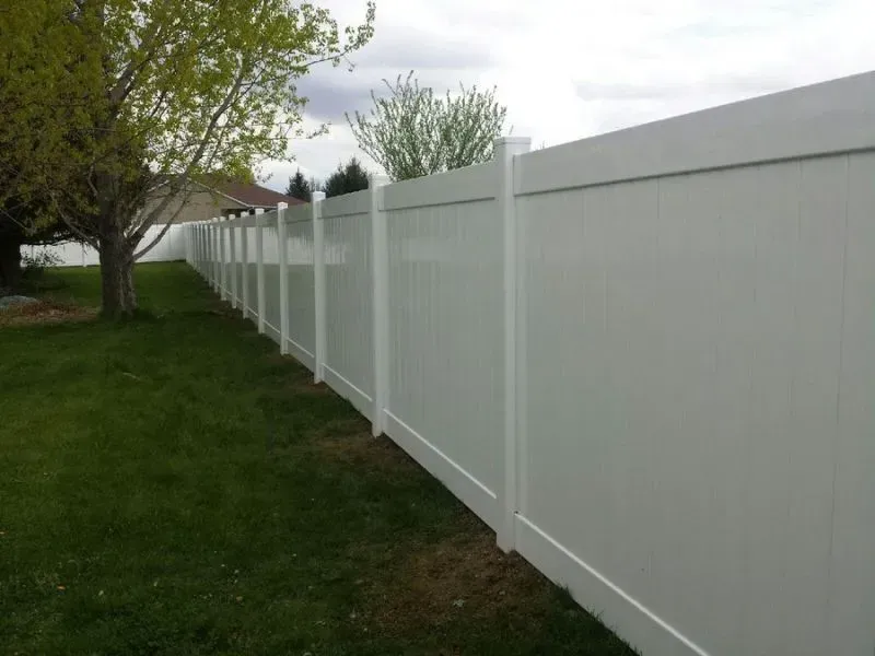 A white fence surrounds a lush green yard.