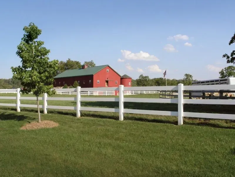 A white fence with a red barn in the background