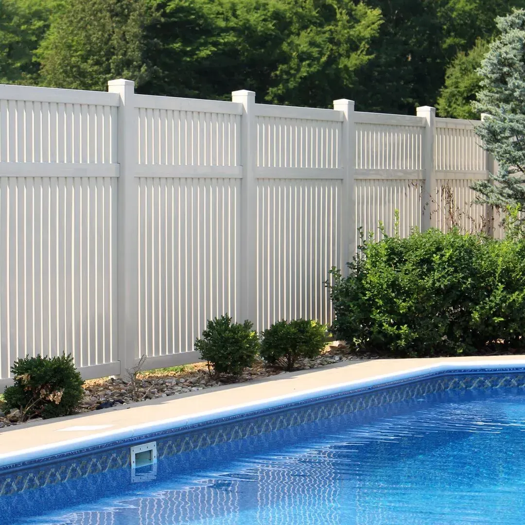 A white fence surrounds a large swimming pool.