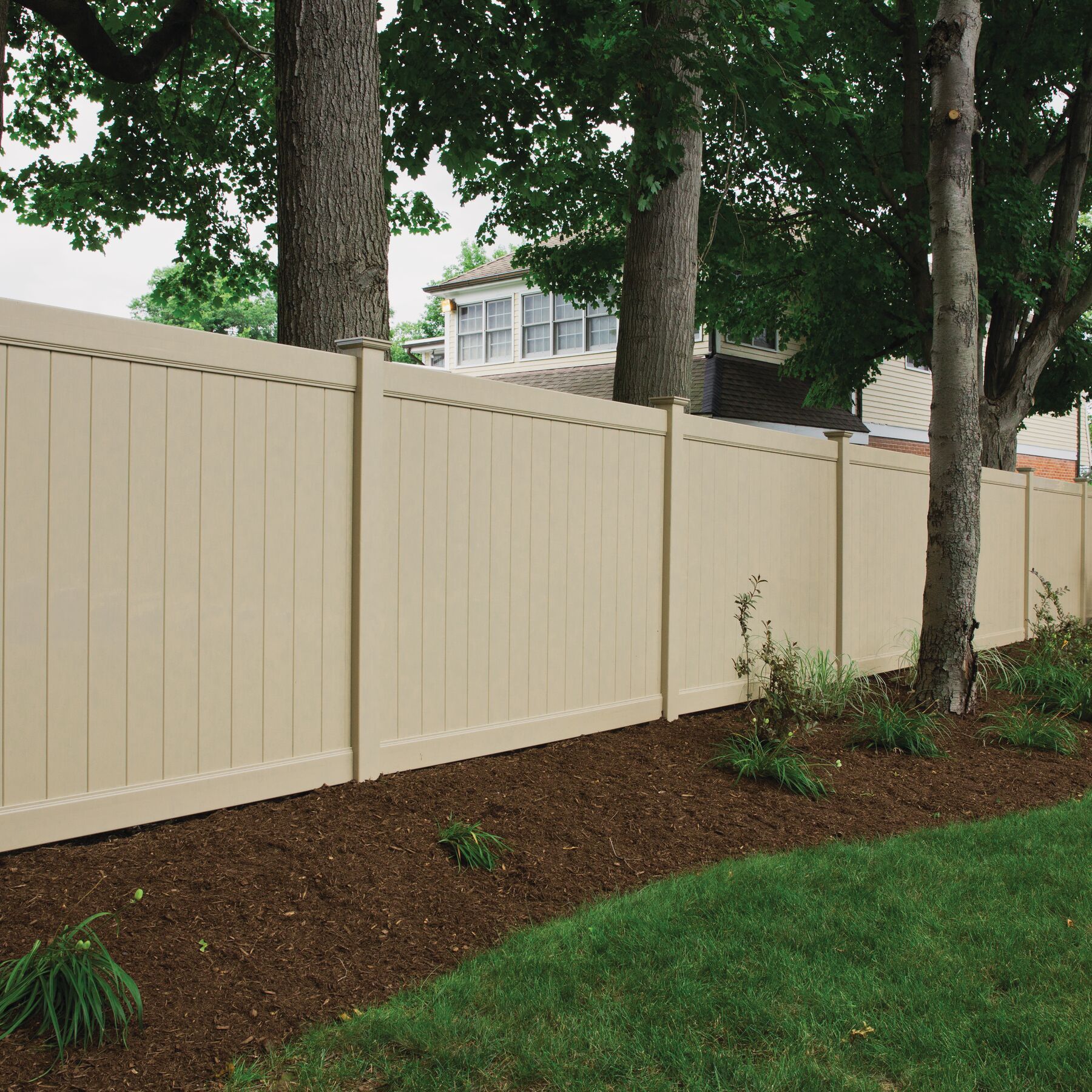 A tan fence with trees in the background