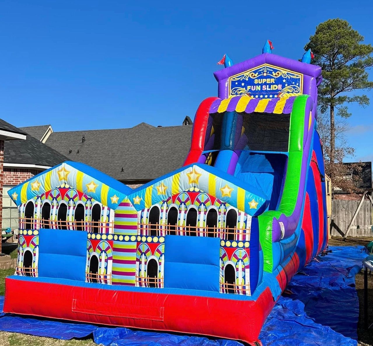 A colorful bouncy house is sitting in front of a house