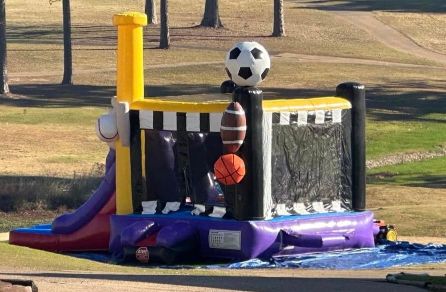 A bouncy house with a soccer ball , basketball , and football on top of it.