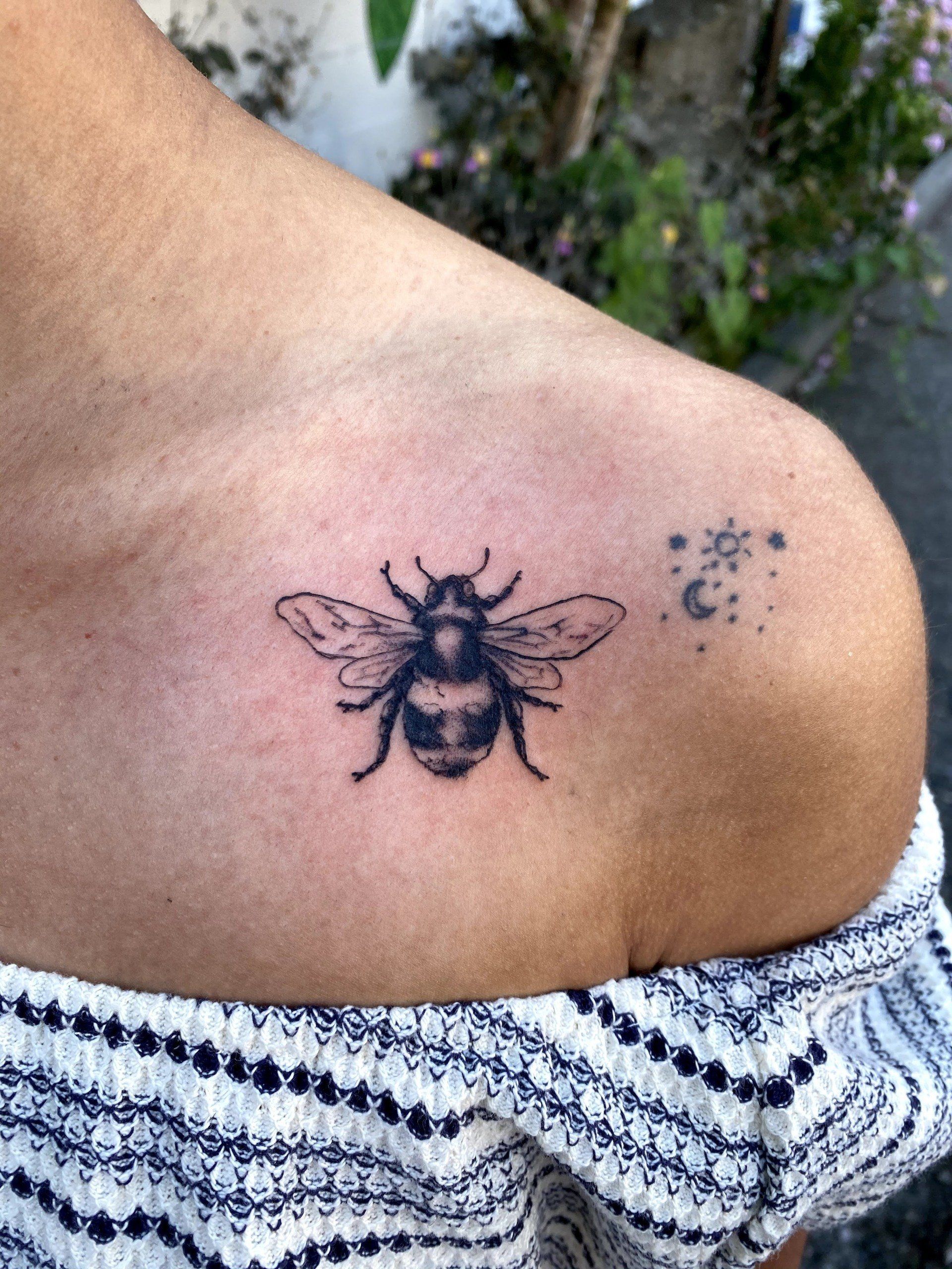 A woman has a bee tattoo on her shoulder