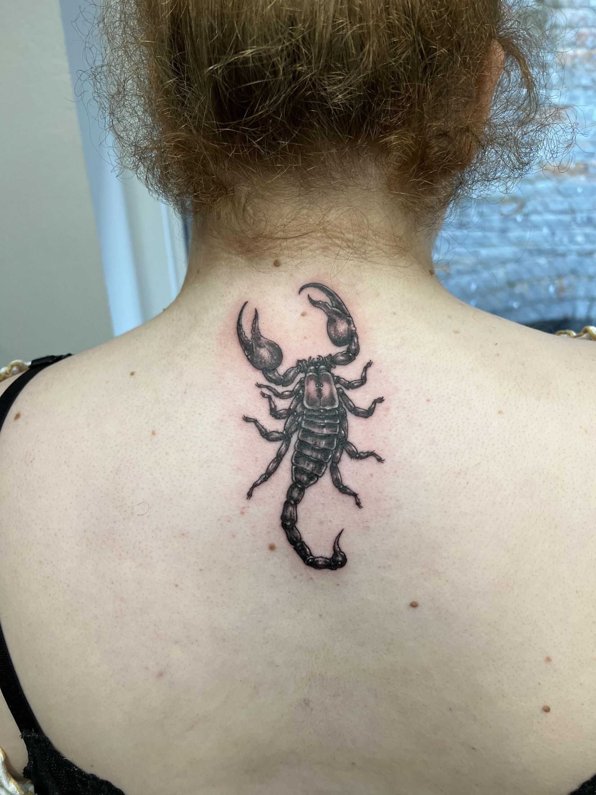 A woman has a tattoo of a scorpion on her back