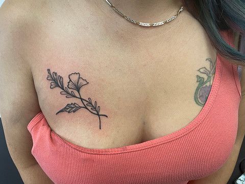 A woman has a tattoo of a flower on her chest.
