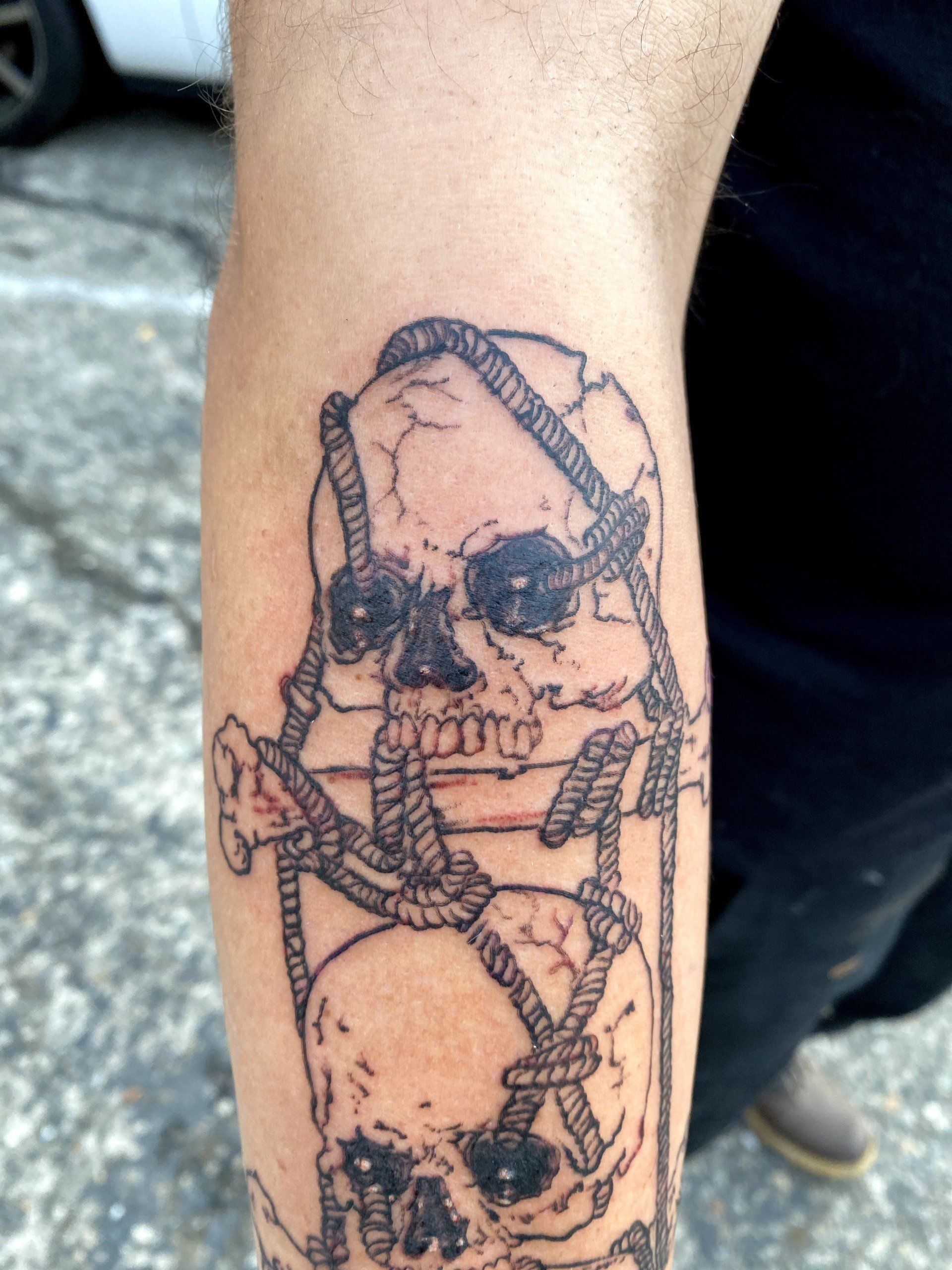 A person has a tattoo of a skull with ropes around it