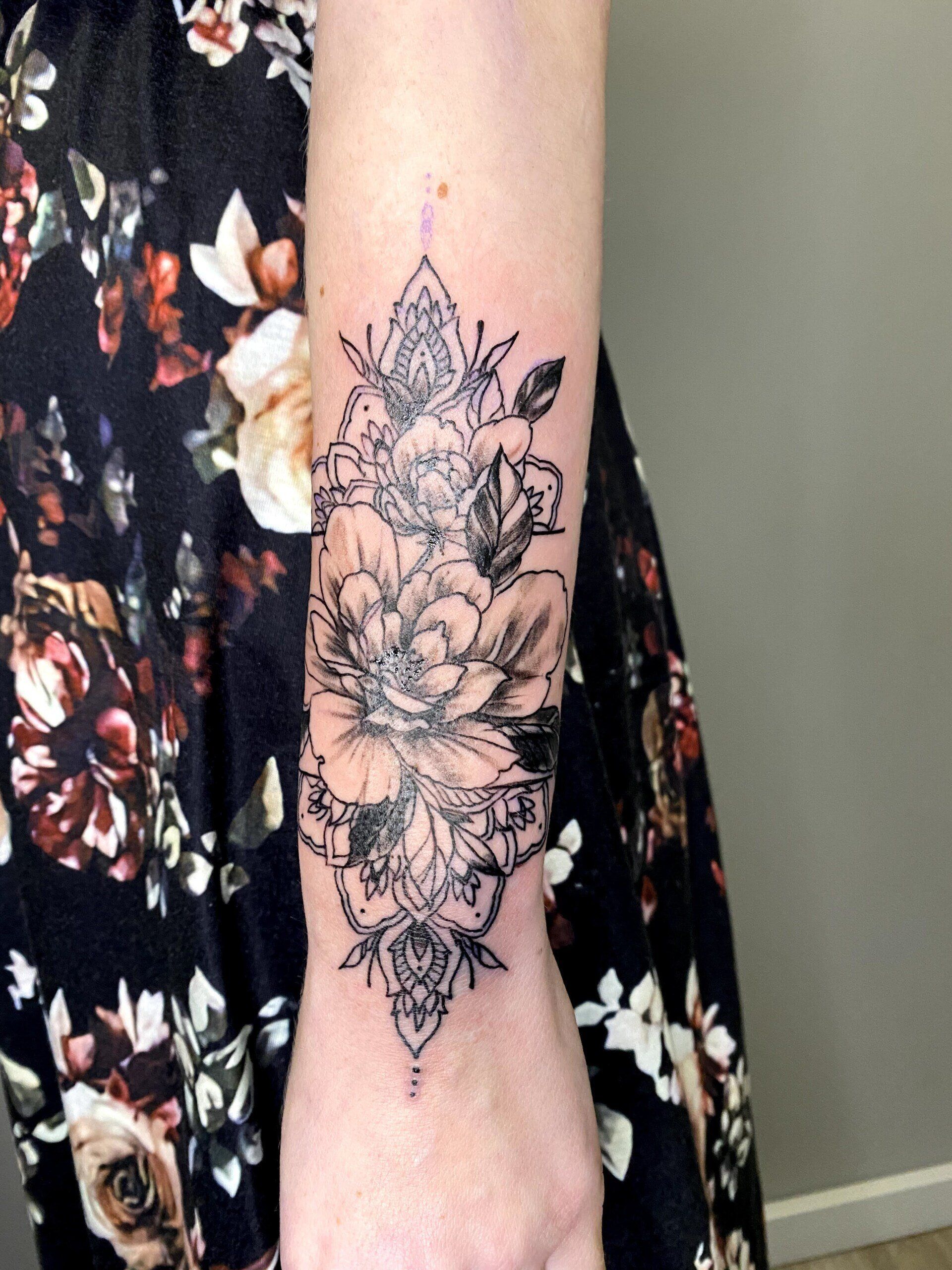A woman has a tattoo of flowers on her forearm.